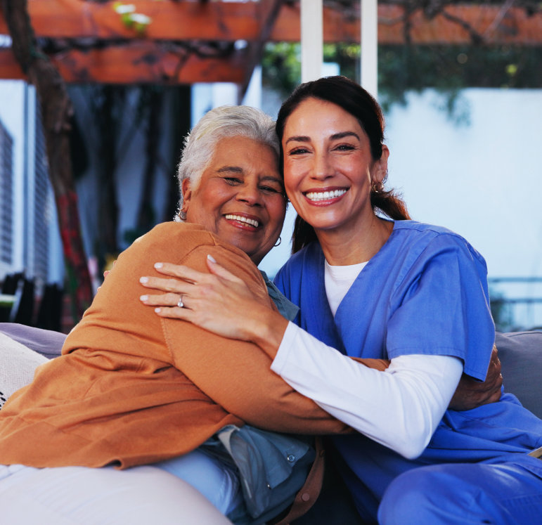 A female caregiver and an elderly woman hugging each other