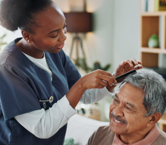 A female caregiver grooming an elderly man