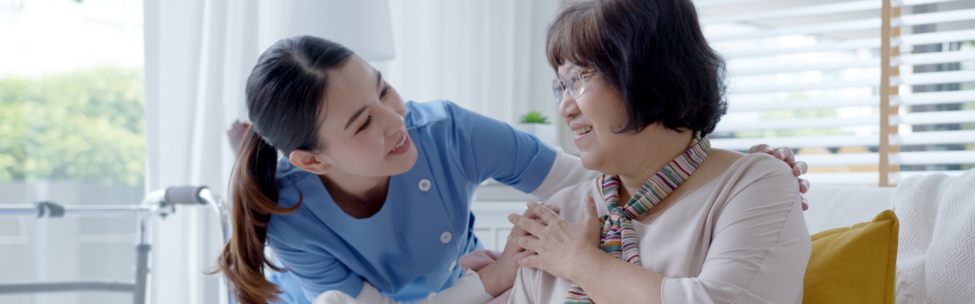 A female caregiver and an elderly woman looking to each other