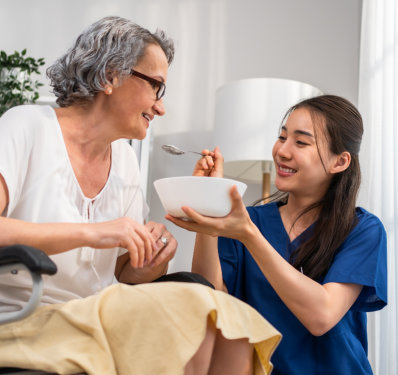 A female caregiver feeding an elderly woman