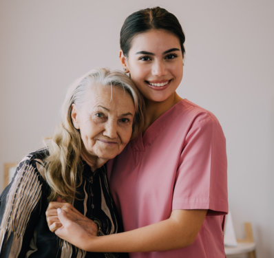 An elderly woman hugging the female caregiver