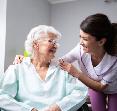 An elderly woman and a female caregiver looking at each other