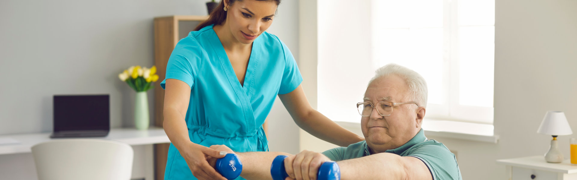 A female caregiver assisting an elderly man lifting weights