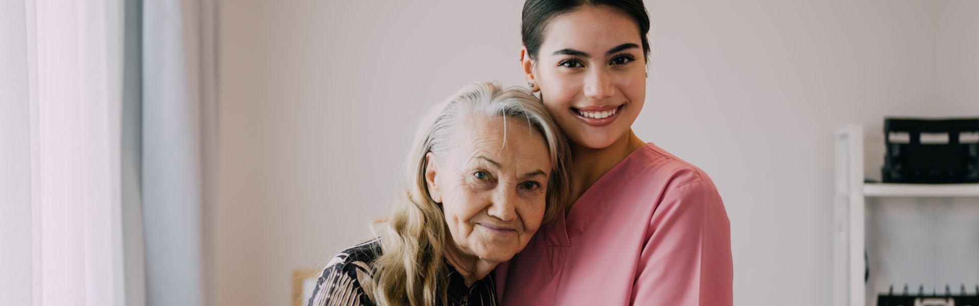 An elderly woman hugging the female caregiver