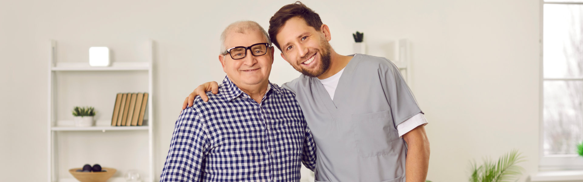 an elderly man and a male caregiver smiling together