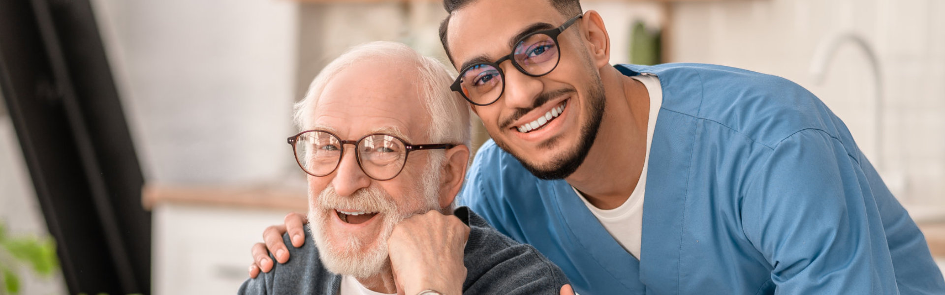 an elderly man and a male caregiver smiling together