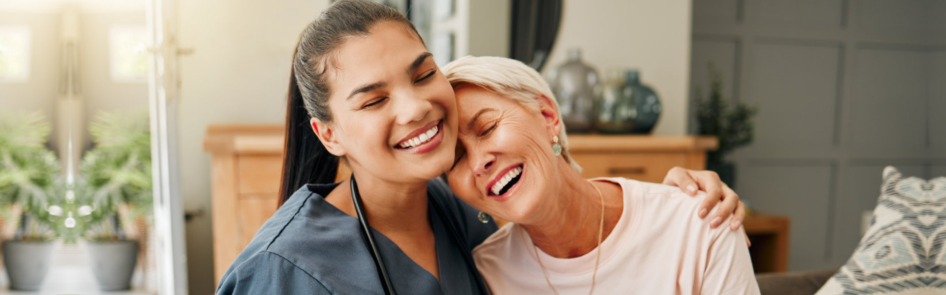 A female caregiver and an elderly woman laughing together